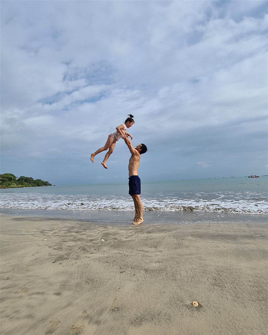 Derrick throwing his daughter into the air on the beach